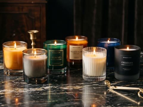 Premium glass candle vessel illuminating a luxury home fragrance environment with warm candlelight